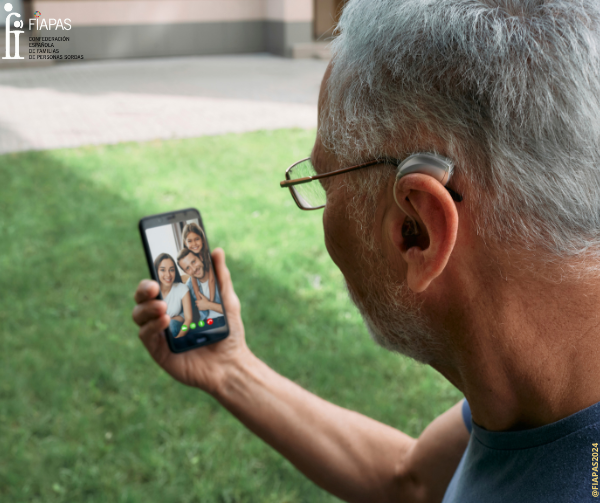 Persona mayor con audífono haciendo una videollamada